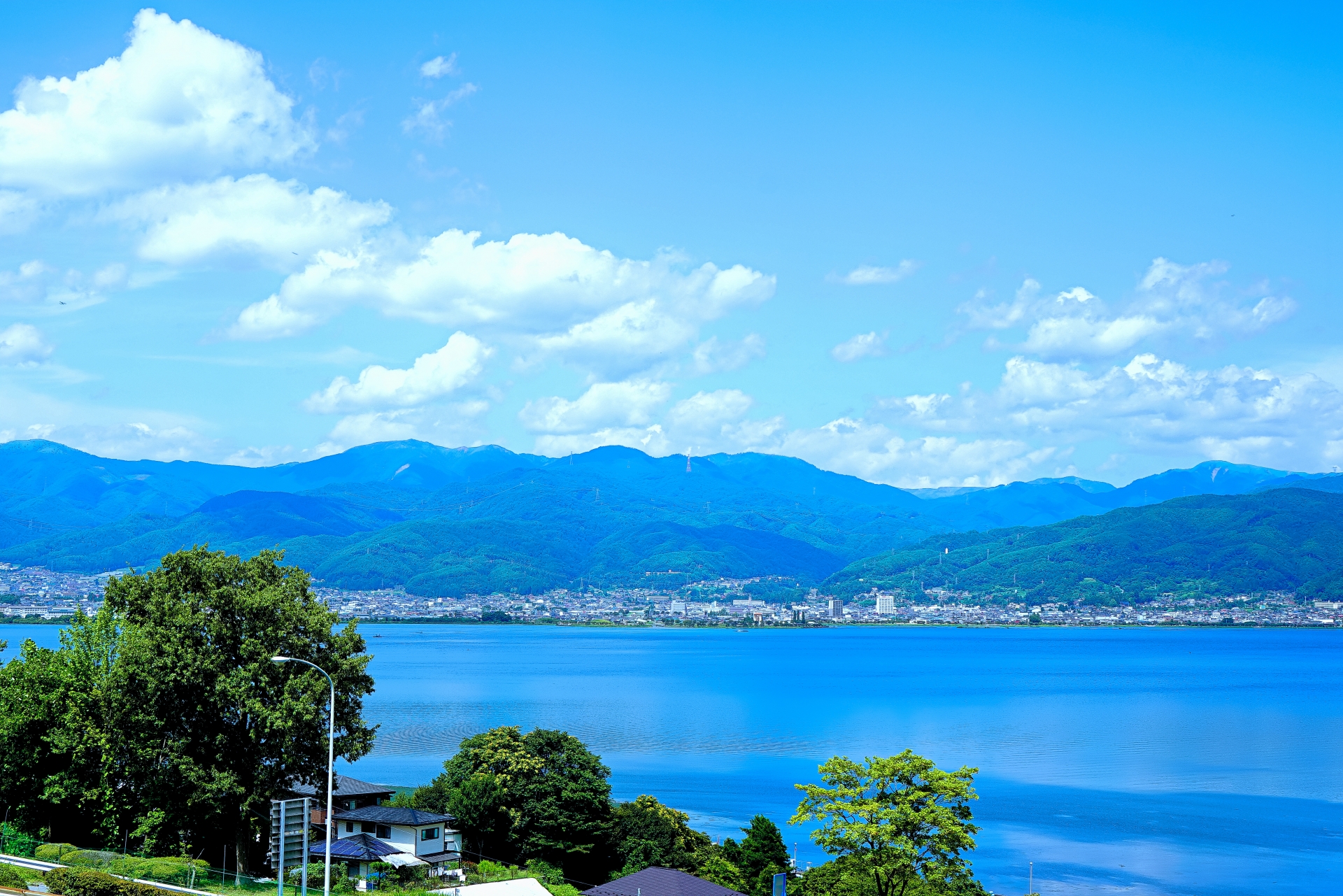 青空の下に広がる諏訪湖と上諏訪温泉の街並み