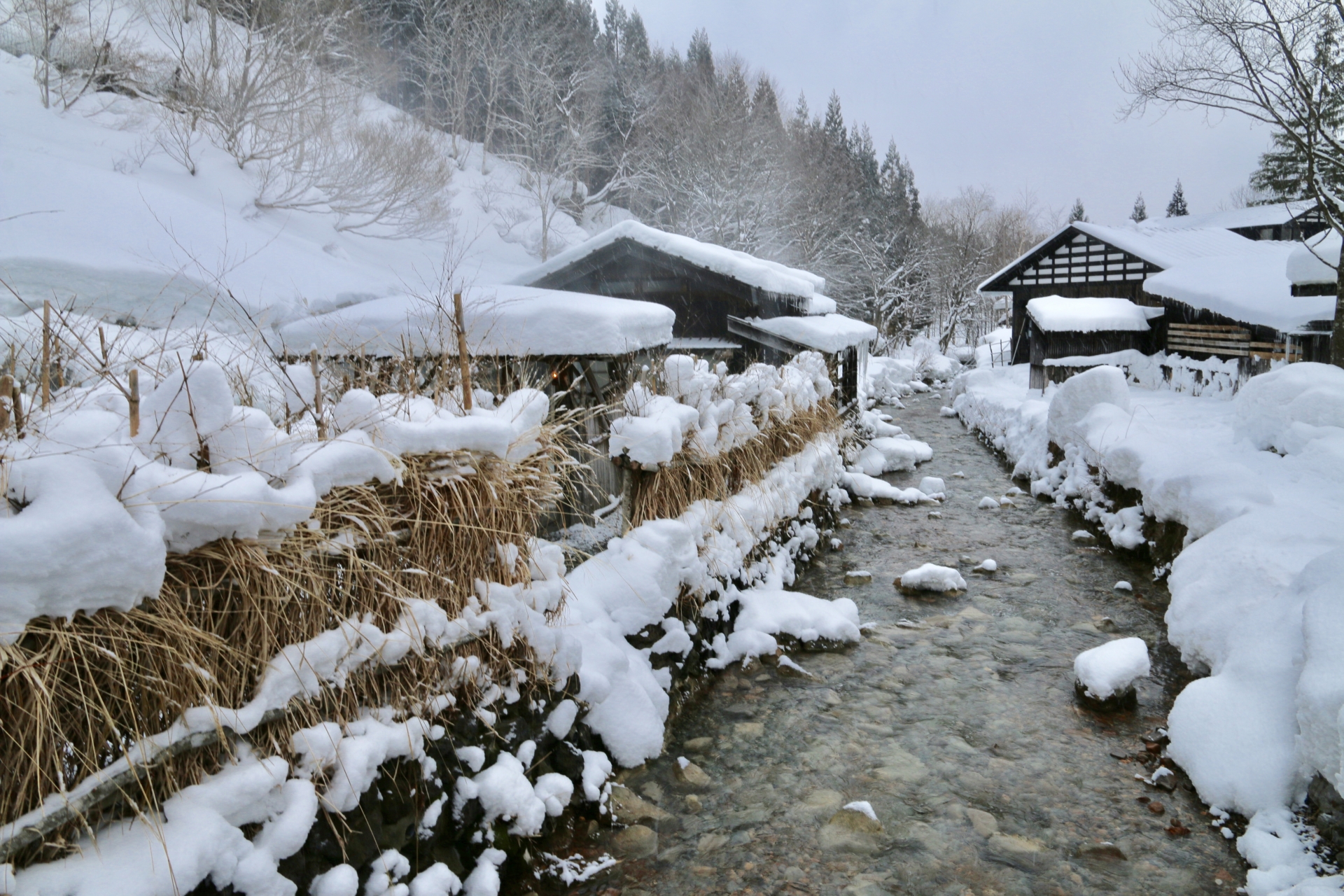 雪に包まれた乳頭温泉郷の温泉宿と小川
